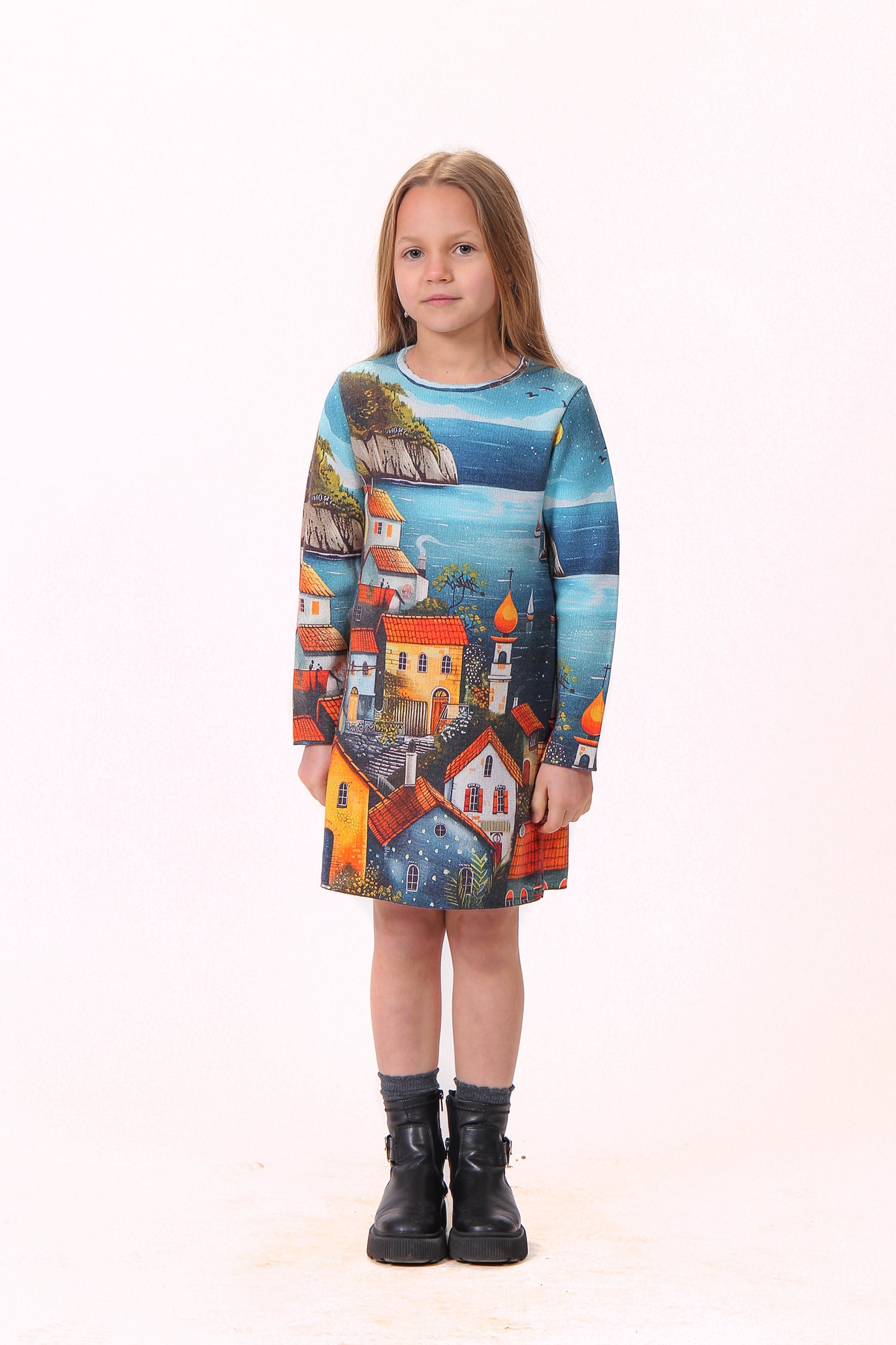 Devojčica u haljini “Ostrvo” stoji, dok lagana tkanina prati njeno telo.